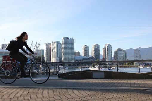 Vancouver, Canada – June 25, 2022: A young female riding a bicycle in downtown Vancouver, Canada