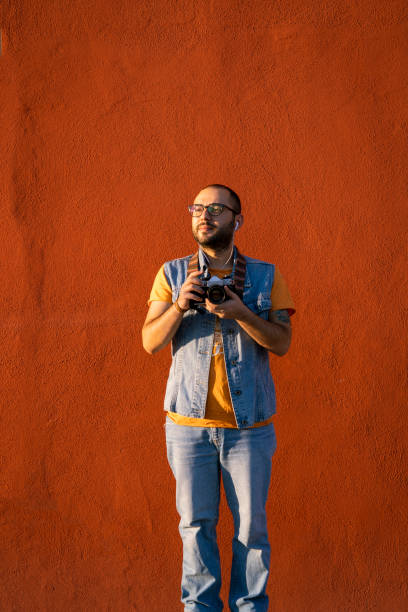 A photographer walking past an orange wall. stock photo