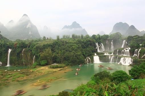 A beautiful long exposure aerial view of the cascading waterfall in the green forest in Guilin