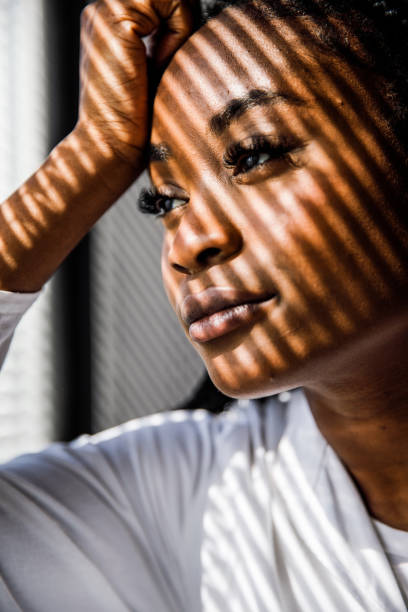 istock Female scientist standing by the window, blind shades playing on her face while she takes a break from work 1446848463
