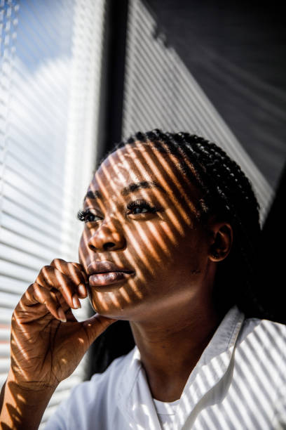 istock Female scientist standing by the window, blind shades playing on her face while she takes a break from work 1446848465