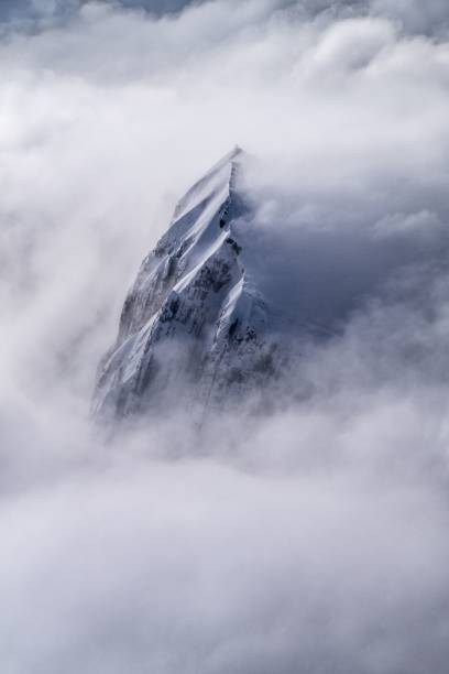 istock Vertical of a snowy mountain in clouds. 1446848878