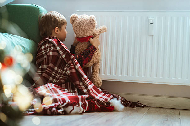 istock cute little boy wrapped id plaid sitting by heater warming teddy bear paws 1446848985