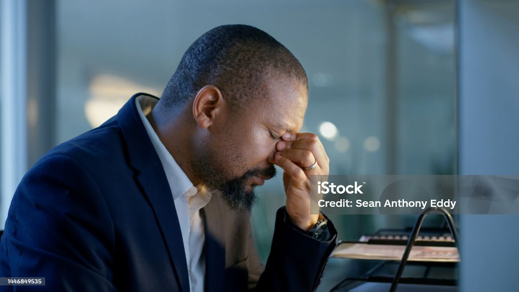 Headache, stress and black man in night office working late or overtime for project deadline. Mental health, burnout and tired businessman from Nigeria in company workplace, exhausted and overworked. 40-44 Years Stock Photo