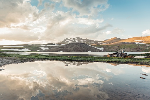 A scenic view of Stone Lake with the mount Aragats in Armenia in cloudy sky background