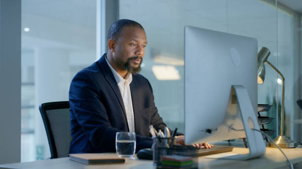 istock Business, computer and black man in office at night working on business proposal, project idea and deadline. Technology, internet and focused male worker doing online research in corporate workplace 1446850648