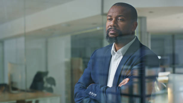 istock Business, corporate CEO and black man at window thinking while look outside. Vision, leadership and management, lawyer or politician man in government advisory office planning idea for future success 1446854484