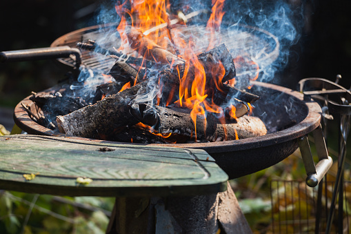 Bright flames of burning branches in the grill - firewood in the brazier before cooking