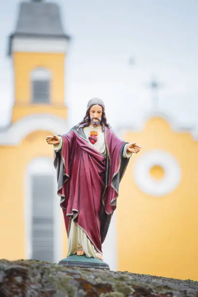 Photo of Porcelain figurine of Jesus on the background of the facade of the church