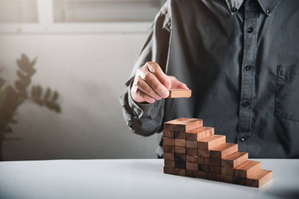 istock Business hand arranging put wooden block stacking step stair growth success process 1446862530