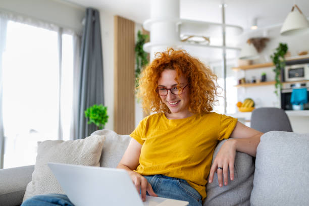 istock Woman sitting with computer on sofa, studying at home, e-learning and remote freelance job concept 1446862586