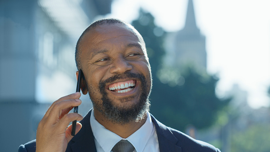 Happy, black man or businessman on a phone call in a city laughing, talking or speaking of a successful deal. Hello, conversation and African person networking in communication about our vision goals