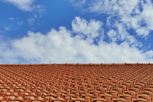 A perspective view of a tiled roof under a blue cloudy sky