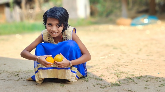 Kid playing with fresh Oranges and smiling while looking at the camera. Selective focus