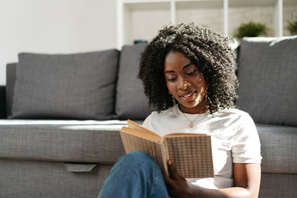 istock African woman reading book at home sitting on sofa 1446866611