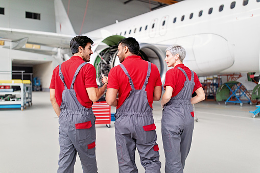 Airplane mechanics discussing planned aircraft maintenance in a hangar