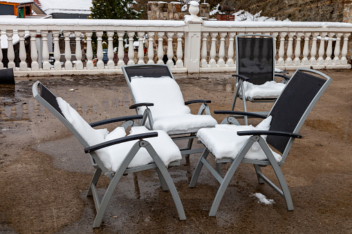 Folding chairs on the summer terrace are covered with snow