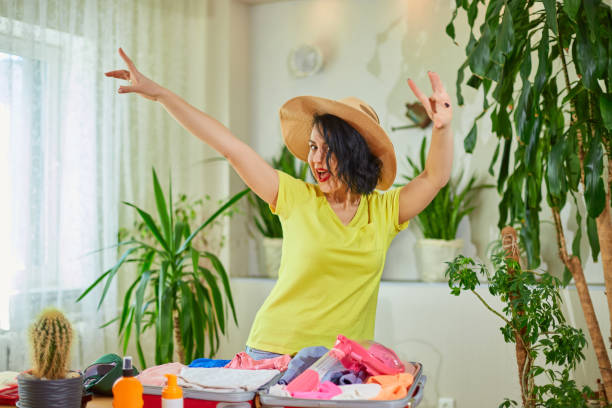 istock Happy woman in hat dancing, packing suitcase, getting ready for summer vacation 1446871964