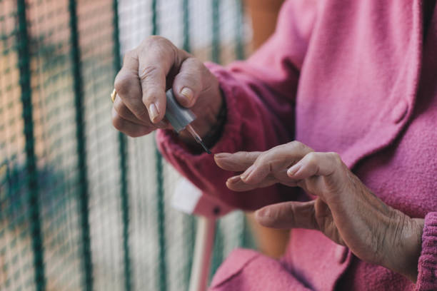 istock unrecognizable elderly woman in robe paints her nails with manicure polish 1446872526