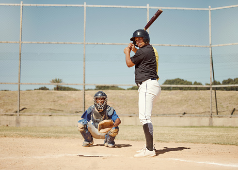Baseball, pitcher and man with a bat on pitch playing a match or sport training as a team. Fitness, sports and men athletes practicing pitching and batting before a softball game on an outdoor field.