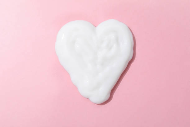 istock Heart made of cream on pink background 1446873936