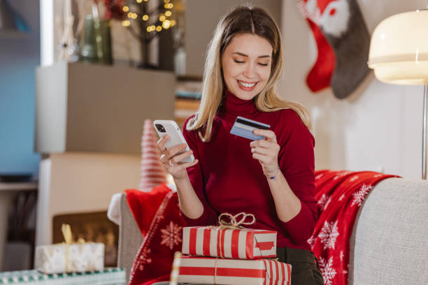 istock Young woman using credit card and smart phone for e-commerce during Christmas time 1446874008