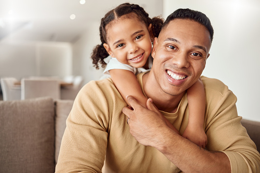 Love, family and girl relax with father on a sofa, playing, bonding and having fun in a living room. Black family, portrait and child enjoy quality time with parent, smiling, hugging and happy