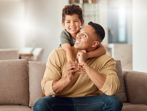 Father, child and sofa with smile, back and together for portrait, happy and home in living room. Family, dad and boy on couch for bonding, playing and happiness in lounge for time, love and relax