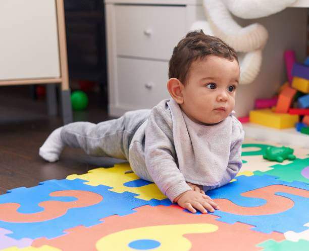 istock Adorable hispanic baby crawling on floor at kindergarten 1446877393