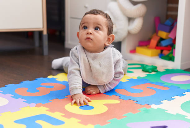 istock Adorable hispanic baby crawling on floor at kindergarten 1446877397