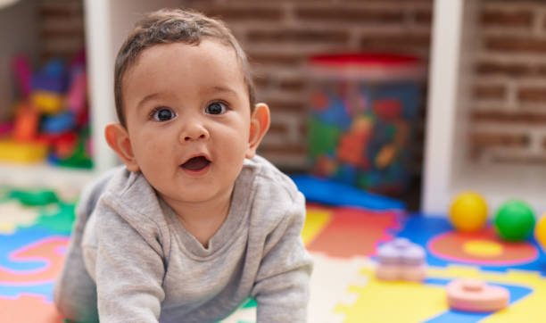 istock Adorable hispanic baby crawling on floor at kindergarten 1446877398