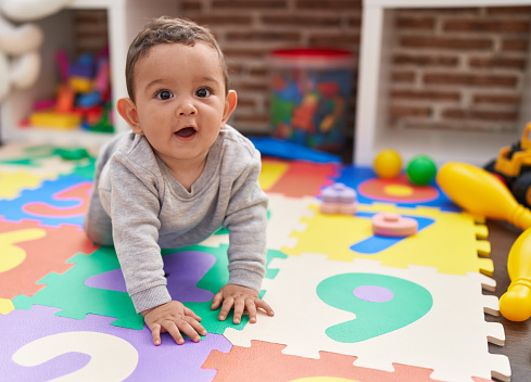 Adorable bebé hispano gateando en el piso en el jardín de infantes photo