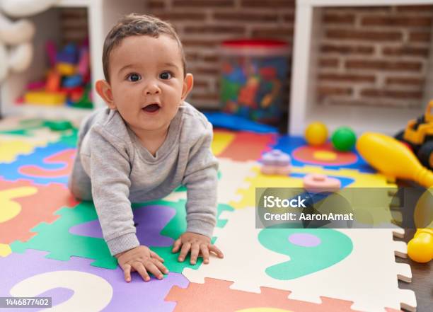 Adorable Hispanic Baby Crawling On Floor At Kindergarten Stock Photo - Download Image Now