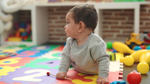 istock Adorable hispanic baby crawling on floor at kindergarten 1446877452
