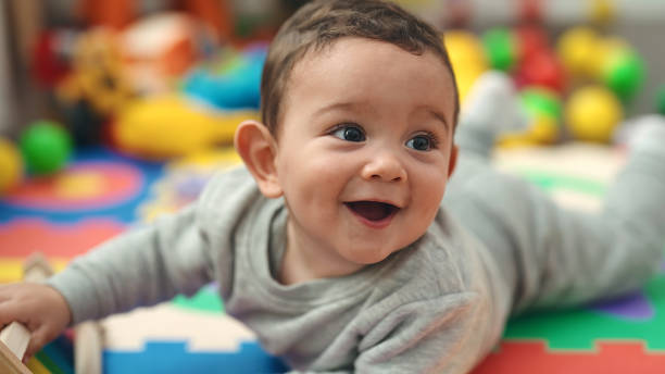 istock Adorable hispanic baby smiling confident lying on floor at kindergarten 1446877453