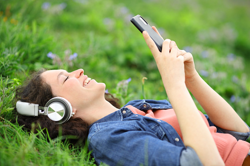 Happy woman listening with headphones and phone