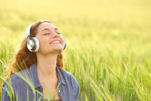 Happy woman listening audio in a field and breathing