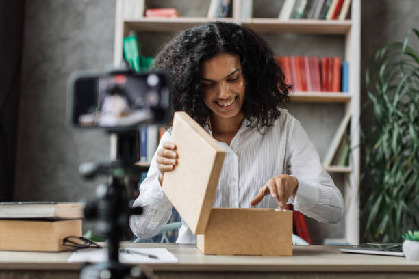 istock Beautiful young multinational woman recording video on camera while unpacking gift box. 1446878563