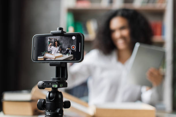 istock Focus on smart phone screen , woman recording video on phone camera while unpacking box with tablet 1446878578