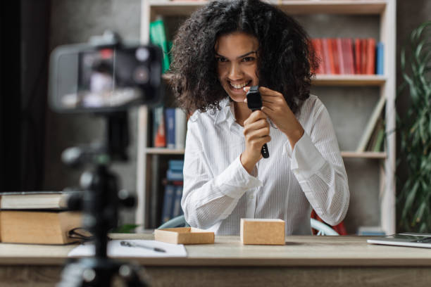 istock African american woman doing live stream while unpacking box with new smart watch. 1446878608