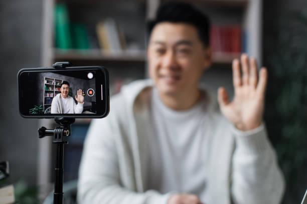 istock Attractive asian man in casual clothes talking and gesturing while recording video on modern phone 1446878663