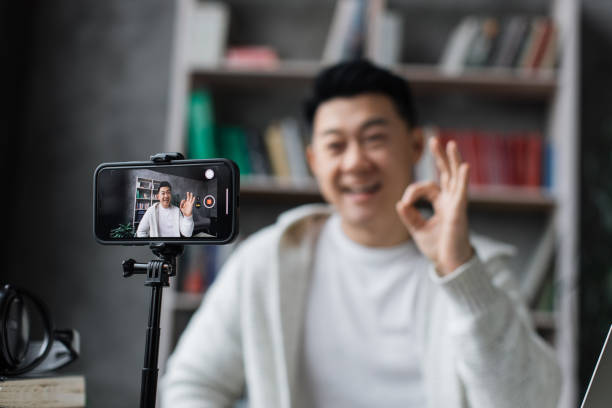 istock Attractive asian man in casual clothes talking and gesturing while recording video on modern phone 1446878667