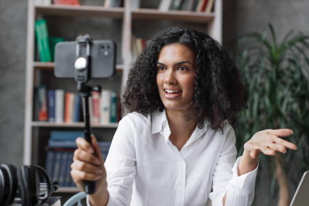 istock Attractive young multinational woman in white shirt taking selfie on her smart phone using stick. 1446878738