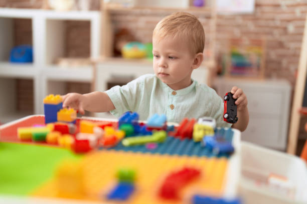 istock Adorable toddler playing with construction blocks holding car at kindergarten 1446879329