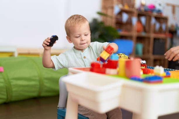 istock Adorable toddler playing with construction blocks holding car at kindergarten 1446879340