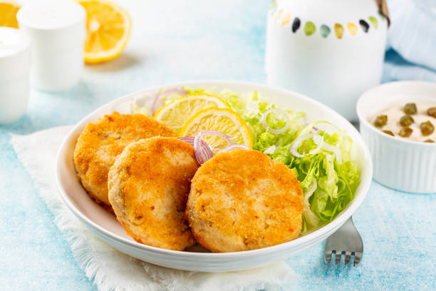 istock Fish cakes or burger, or cutlets. Made from ground perch and tuna with herbs, breaded and fried, served with iceberg salad, lemon slices. 1446881179