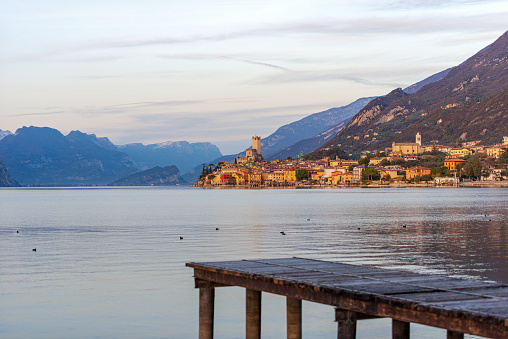 Lake Garda (Lago di Garda) and the small Malcesine town with the castle at sunset. Verona province, Italy, Veneto, southern Europe. On background the coast of the Lombardy and Trentino-Alto Adige.