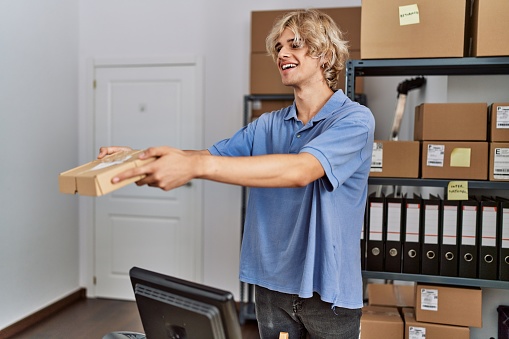 Young blond man ecommerce business worker holding package at office