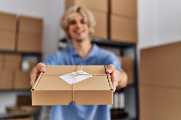 istock Young blond man ecommerce business worker holding package at office 1446884642