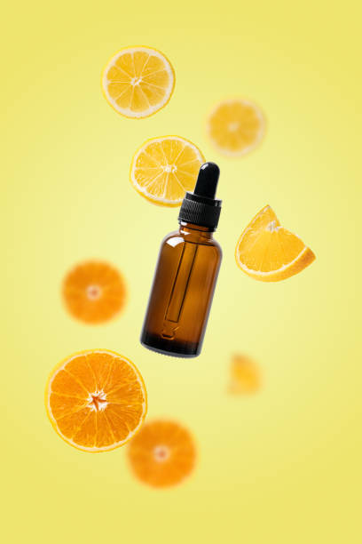 Beauty serum with lemons and oranges isolated on yellow background stock photo